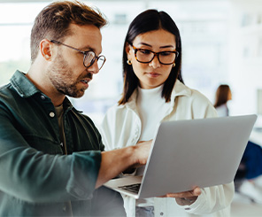 two people talking with laptop in hand